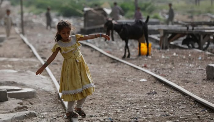 A girl balances herself while walking on an abandoned railway track in a slum area in Karachi, Pakistan July 10, 2023. — Reuters