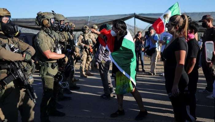 A demonstrator draped in a Mexican flag gestures at US federal agents blocking a road leading to an agricultural facility where U.S. federal agents and immigration officers carried out an operation, in Camarillo, California, US, July 10, 2025. — Reuters