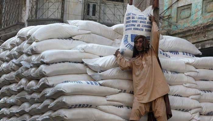 The undated image shows a labourer carrying a sack of refined sugar. —APP File