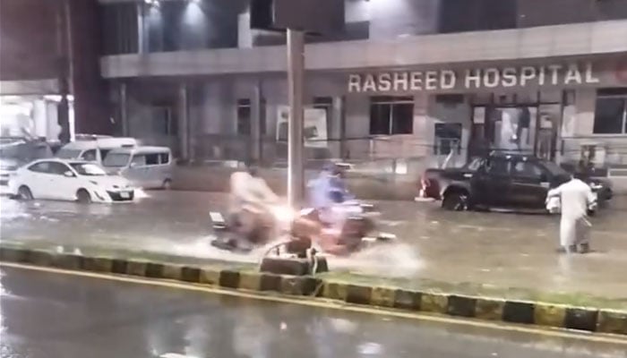 The image shows a road in Lahore submerged in rainwater as traffic passes through on July 16, 2025. — X@iamfahadsb/Screenshot