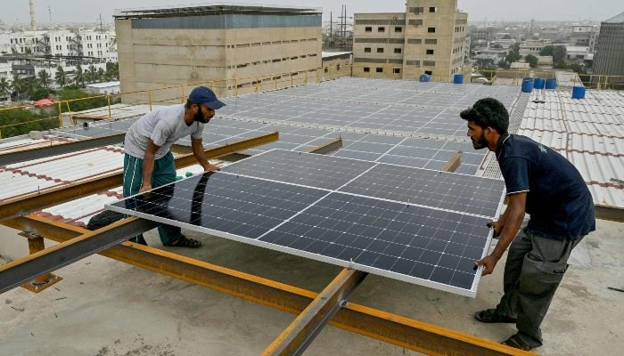 Quiet solar rush putting pressure on national grid 11 In this photograph taken on July 2, 2025, technicians install solar panels on the rooftop of a factory in Karachi. — AFP
