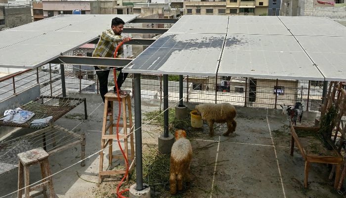 In this photograph taken on June 24, 2025, Arsalan Arif, a local businessman, cleans solar panels installed on his houses rooftop in Karachi. — AFP