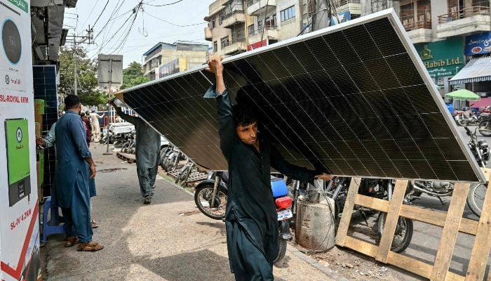 Quiet solar rush putting pressure on national grid 10 In this photograph taken on June 23, 2025, a labourer carries a solar panel along a road in Karachi. — AFP
