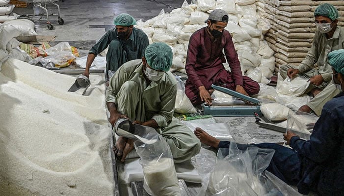 A representational image showing workers preparing sugar bags at a warehouse. — AFP/File