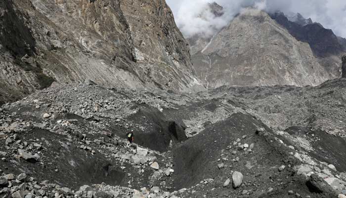 Tariq Jamil walks with a hiking stick to check the ice on the Shisper glacier, near Hassanabad village, Pakistan, October 10, 2023. — Reuters