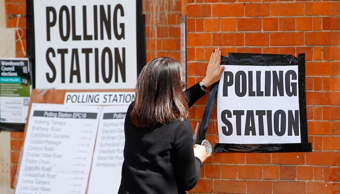 A woman attaches a sign on the wall of a polling station during the local elections in London, Britain, May 5, 2022. — Reuters