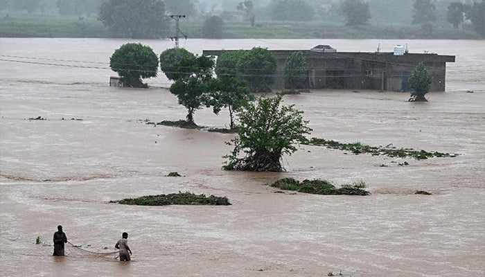 Local people catch fish in the floodwaters near a partially submerged house during heavy monsoon rains at the Ladian village of Rawalpindi on July 17, 2025. — AFP