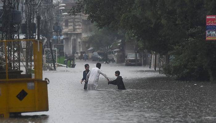 People wade through the flooded street after during the monssoon rain in Rawalpindi, on July 17, 2025. — Reuters