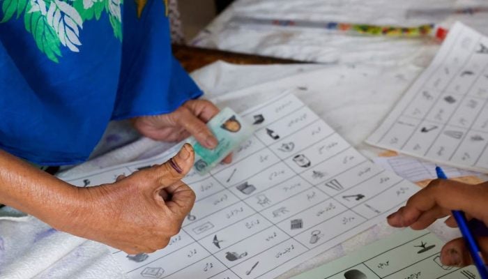 A voter with an ink mark on the thumb goes through paperwork to cast a vote during the general election in Karachi, Pakistan February 8, 2024. — Reuters