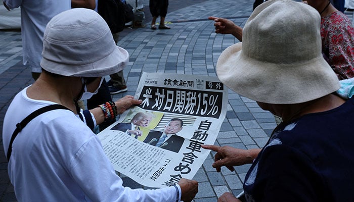 People react as they read a special edition of Yomiuri Shimbun newspaper reporting the tariff deal agreement between US and Japan, in Tokyo on July 23, 2025. — Reuters