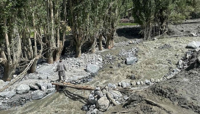 Image shows a man crossing a stream while visiting the flood-hit Kondus Valley of Ghanche district in the Gilgit Baltistan on July 24, 2025. — AFP