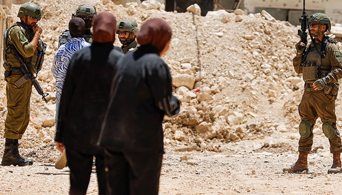 Israeli soldiers speak with a Palestinian woman, outside of Jenin camp, during an Israeli military operation, in the Israeli-occupied West Bank, July 8, 2025. — Reuters
