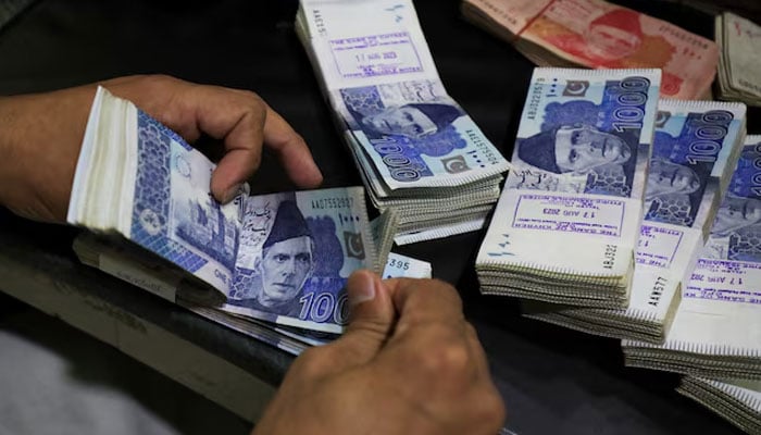 An employee counts Pakistani rupee notes at a bank in Peshawar on August 22, 2023. — Reuters