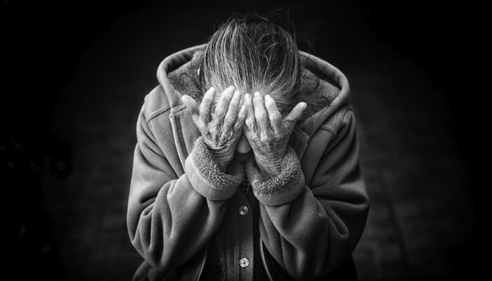 This representational image shows a woman with her head buried in the palms of her hands. — Unsplash