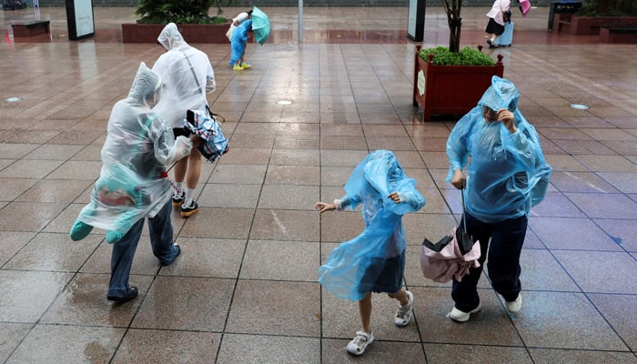 People use umbrellas and raincoats to shield themselves from heavy rain and high winds after Tropical Storm Co-May made landfall in a nearby city in Shanghai, China, on July 30, 2025. — Reuters
