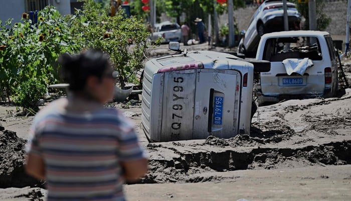 A person looks at flood-damaged cars in the Huairou district, on the outskirts of Beijing, following heavy rains over the past few days on July 30, 2025. — AFP