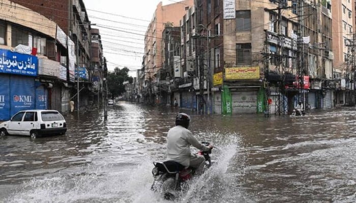 A man rides a motorcycle through a flooded street after heavy rainfall in Lahore on July 23, 2025. —AFP