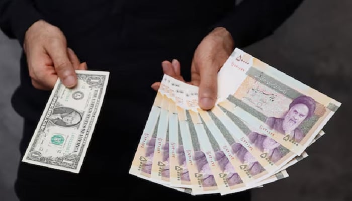 A currency dealer poses for a photo with a one US dollar bill and Iranian rials in an exchange shop in Tehran, Iran, December 25, 2022.—Reuters