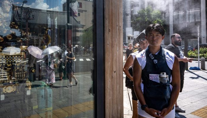 Rickshaw drivers stand underneath artificial mist to cool down near a shopping street as pedestrians use umbrellas to shelter from the sun at the Asakusa district near Sensoji Temple, on a hot day in Tokyo, Japan, on July 28, 2025. — AFP