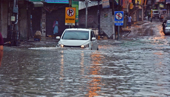Commuters drive across a road at Dingi Khoi area during heavy monsoon rain in Rawalpindi. — Online/File