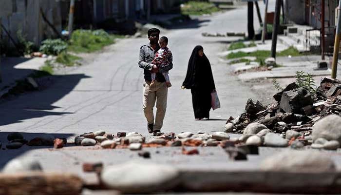 A Kashmiri familiy walks past a blockade put up by residents to prevent Indian security force personnel from entering their neighborhood, in Srinagar, August 20,2019. —  Reuters