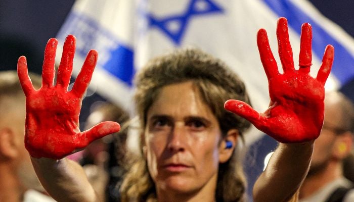A demonstrator displays her hands painted in red to depict blood during an anti-government protest, outside the Israeli Defence Ministry headquarters in Tel Aviv on August 2, 2025. — AFP