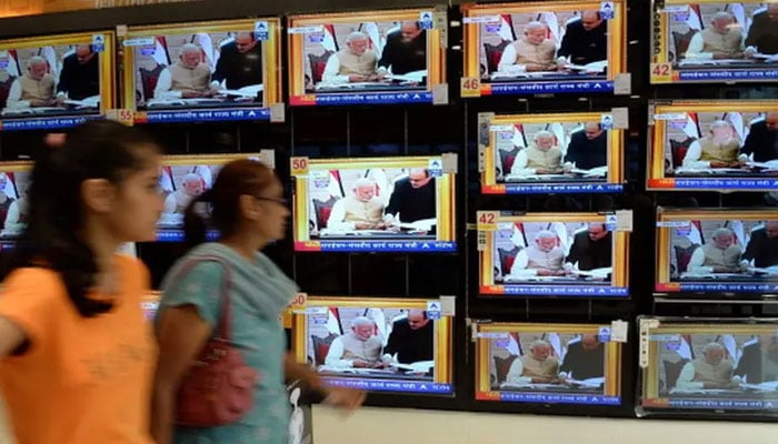 People walk past multiple TV screens showing PM Modi in this undated image. — AFP/FIle
