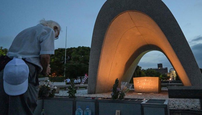 Visitors pray for atomic bomb victims in front of the memorial cenotaph in Hiroshima. — AFP