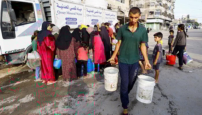 A man carries buckets of water as Palestinians wait to collect water amid shortages, in Gaza City August 6, 2025. — Reuters