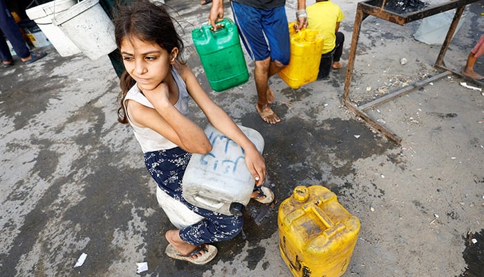 A Palestinian girl waits with containers to collect water amid shortages, in Gaza City August 6, 2025. — Reuters