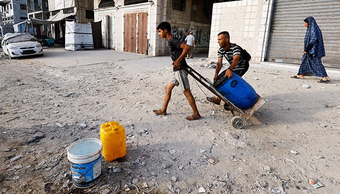 A boy pulls a container on a trolley as Palestinians wait to collect water amid shortages amid shortages, in Gaza City August 6, 2025. — Reuters