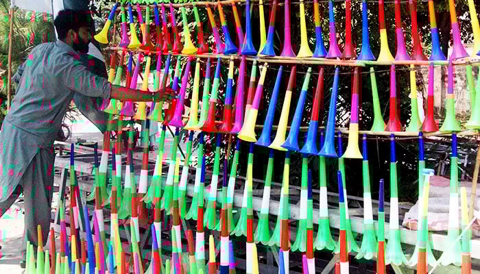 A vendor displays colourful plastic horns at Murree Road in connection with Independence Day alongside a road in Rawalpindi, on August 13, 2022. — Online