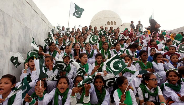 School children wave the national flag and sing patriotic songs at a ceremony to celebrate Independence Day at the mausoleum of Muhammad Ali Jinnah in Karachi. — Reuters