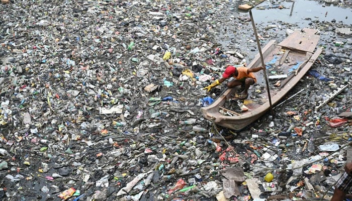 A municipal worker clears plastic and garbage waste choking the Buckingham Canal water flow in Chennai in November 2023. — AFP