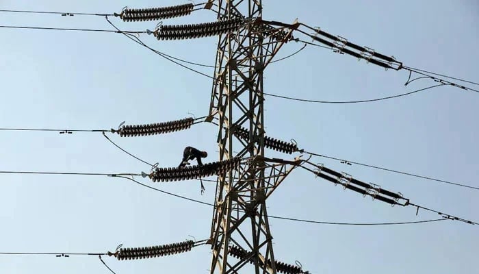 A technician works on porcelain insulators on power transmission tower in Karachi. — Reuters/File