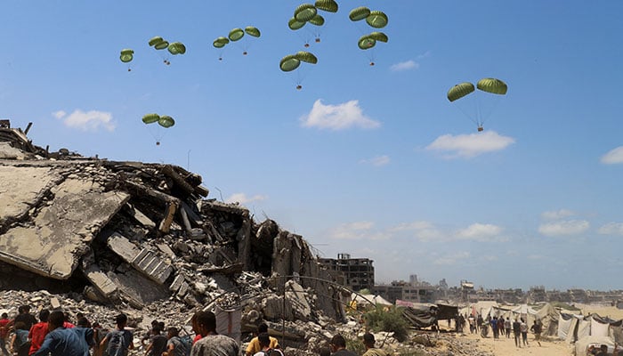 Palestinians run towards parachutes carrying aid packages airdropped over northern Gaza Strip, August 7, 2025. — Reuters