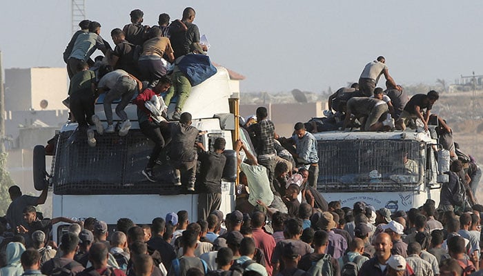Palestinians climb onto trucks as they seek aid supplies in Khan Younis, southern Gaza Strip, August 4, 2025. — Reuters