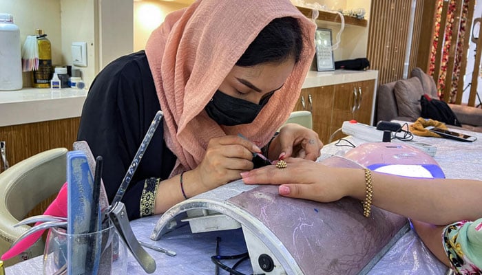 A beautician paints a customers nails at a beauty salon in Kabul on July 23, 2023. — AFP