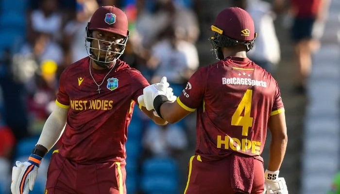 Sherfane Rutherford (L) and Shai Hope (R) of West Indies celebrate a 50-run partnership during the second ODI cricket match between West Indies and Pakistan at Brian Lara Cricket Academy in Tarouba, San Fernando, Trinidad and Tobago on August 10, 2025. —AFP