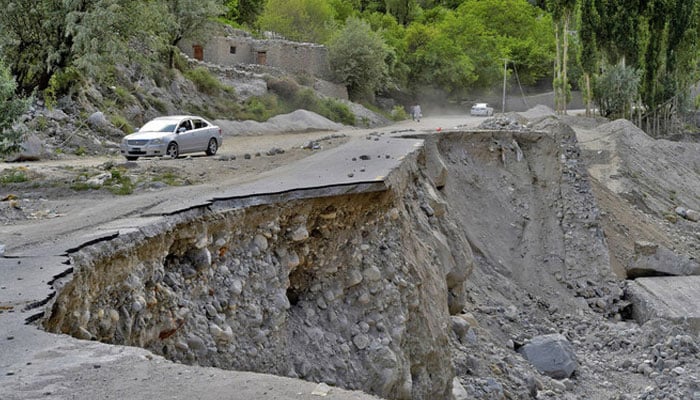 A vehicle drives past a partially collapsed section of the Karakoram Highway damaged after a lake outburst near Hassanabad village of Gilgit-Baltistan region, June 9, 2022. — AFP