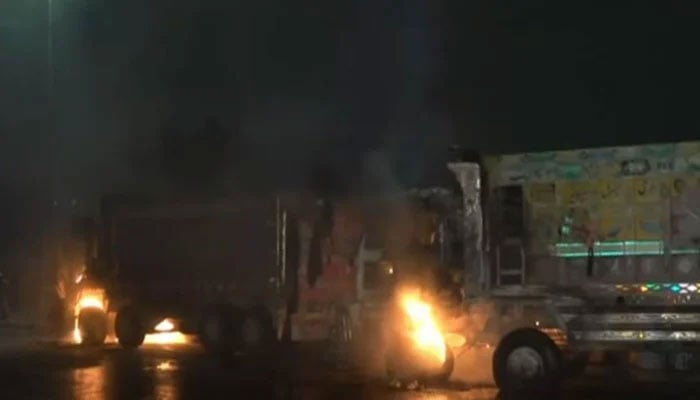 The image shows dumper trucks set on fire by mob at Rashid Minhas Road in Karachi on August 10, 2025. — Screengrab via Geo News