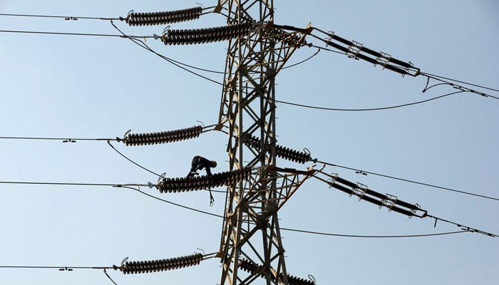 A technician works on porcelain insulators on power transmission tower in Karachi. — Reuters/File