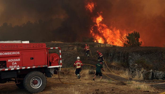 Firefighters work to extinguish a wildfire approaching Trancoso, Portugal, August 13, 2025. — Reuters