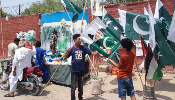 Children are seen buying national flags from roadside stalls, brimming with excitement to celebrate Independence Day with full patriotic spirit in Bahawalpur on August 13, 2025. — APP