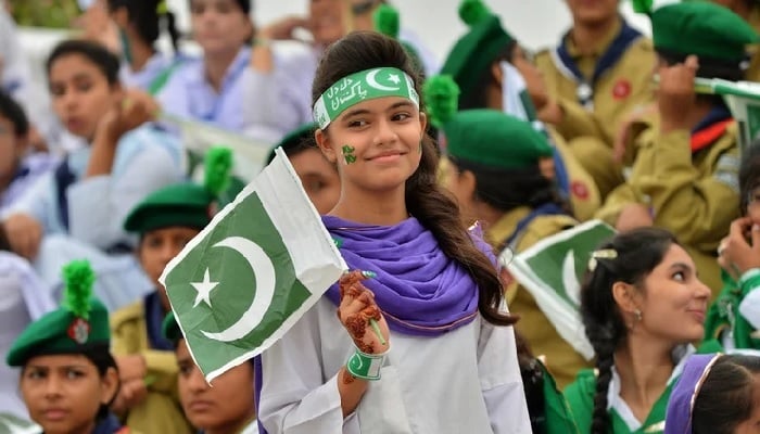 Students wave the national flag during Independence Day celebrations at the mausoleum of the Father of the Nation, Quaid-i-Azam Mohammad Ali Jinnah, in Karachi on August 14, 2018. — AFP