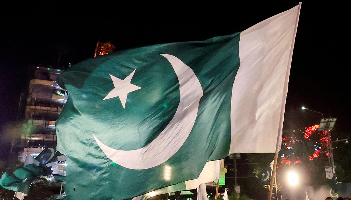 People wave national flags as they gather on the eve of Independence Day in Lahore on August 13, 2025. — Reuters