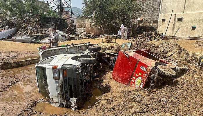 People walk past damaged vehicles and scattered debris after a road washed out following a flash flood in Mingora, the main city of Swat Valley, in monsoon-hit northern mountainous Khyber Pakhtunkhwa province on August 16, 2025. — AFP