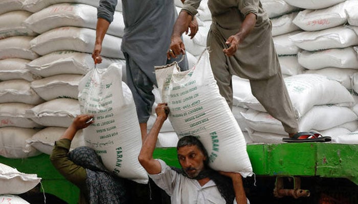 A labourer unloads bags of sugar from a delivery truck to a market in Karachi. — Reuetrs/File