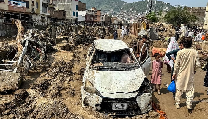 People gather near a damaged vehicle and scattered debris after the road washed out following a flash flood in Swats Mingora in monsoon-hit Khyber Pakhtunkhwa on August 16, 2025. — AFP