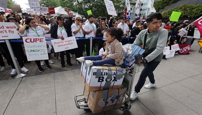 A man pushes a cart with a child seated atop boxes as Air Canada flight attendants said they will remain on strike and challenge a return-to-work order they called unconstitutional, defying a government decision to force them back to their duties, at Vancouver International Airport in Richmond, British Columbia, Canada, August 17, 2025.— Reuters